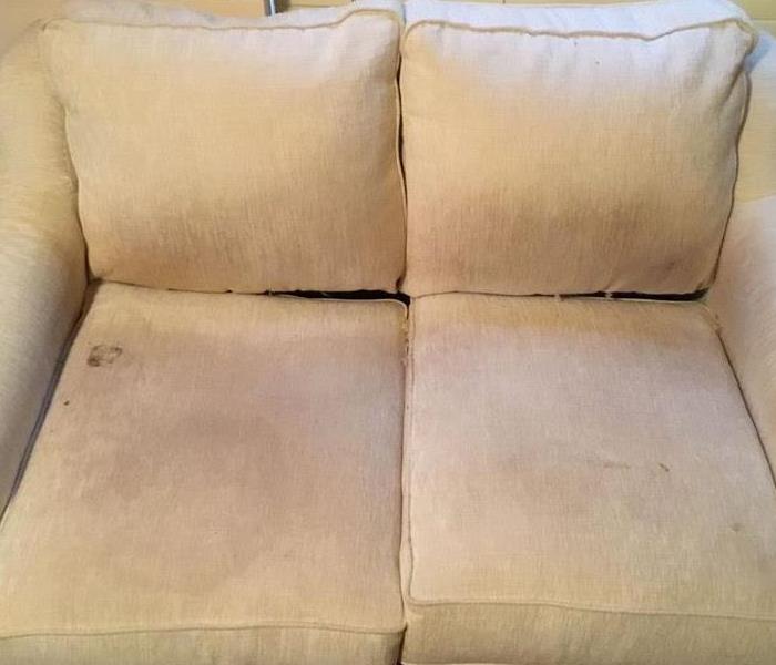 Beige loveseat with various stains